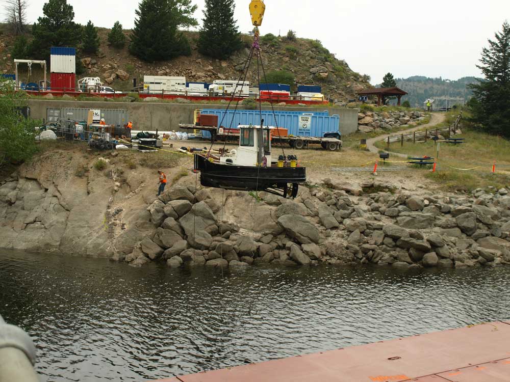 起重机将小型拖船降下水库。