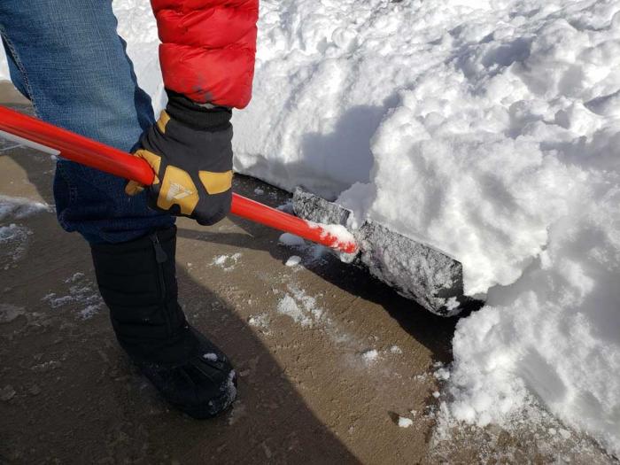 一个充满雪的铲子被抬起人行道。
