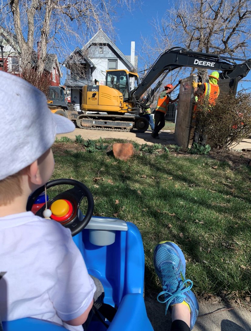 一个男孩看工作者和一台挖掘机。