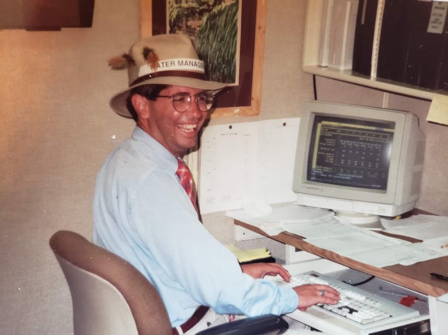 一个男人在他的桌子上用一个巨大的电脑笑着露营者。